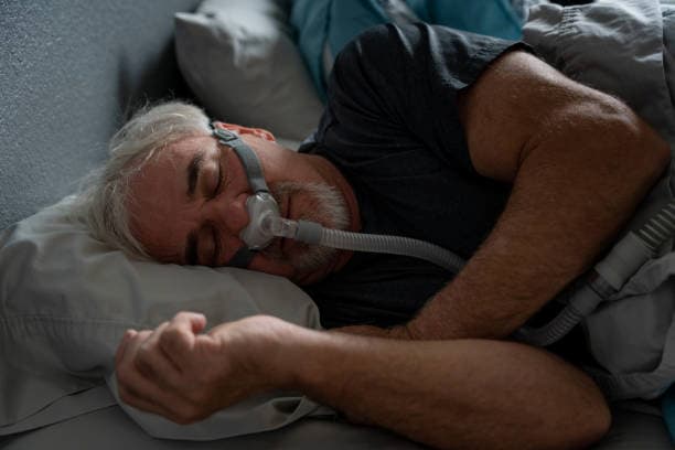 hombre mayor durmiendo con máscara para apnea del sueño
